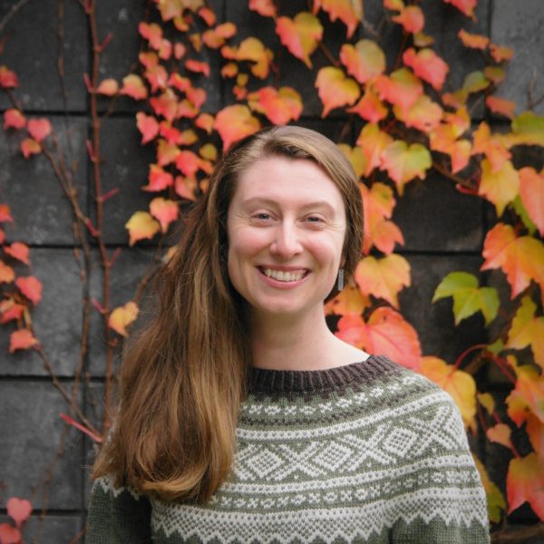 Hannah Harrison A picture of a white woman smiling with a background of ivy in the fall.