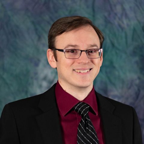 Headshot of a white man in a suit and tie