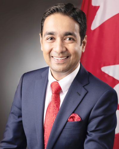 an image of a southeast asian man sitting in front of the canadian flag