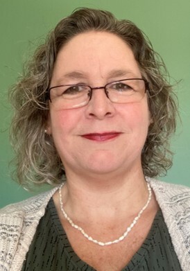 A headshot of a white woman with glasses and red lipstick